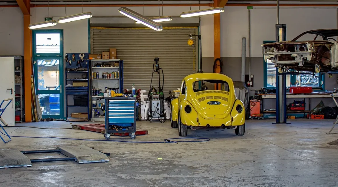 Vue de jour d'un garage moderne avec une voiture couverte, des plans et des outils sur un établi