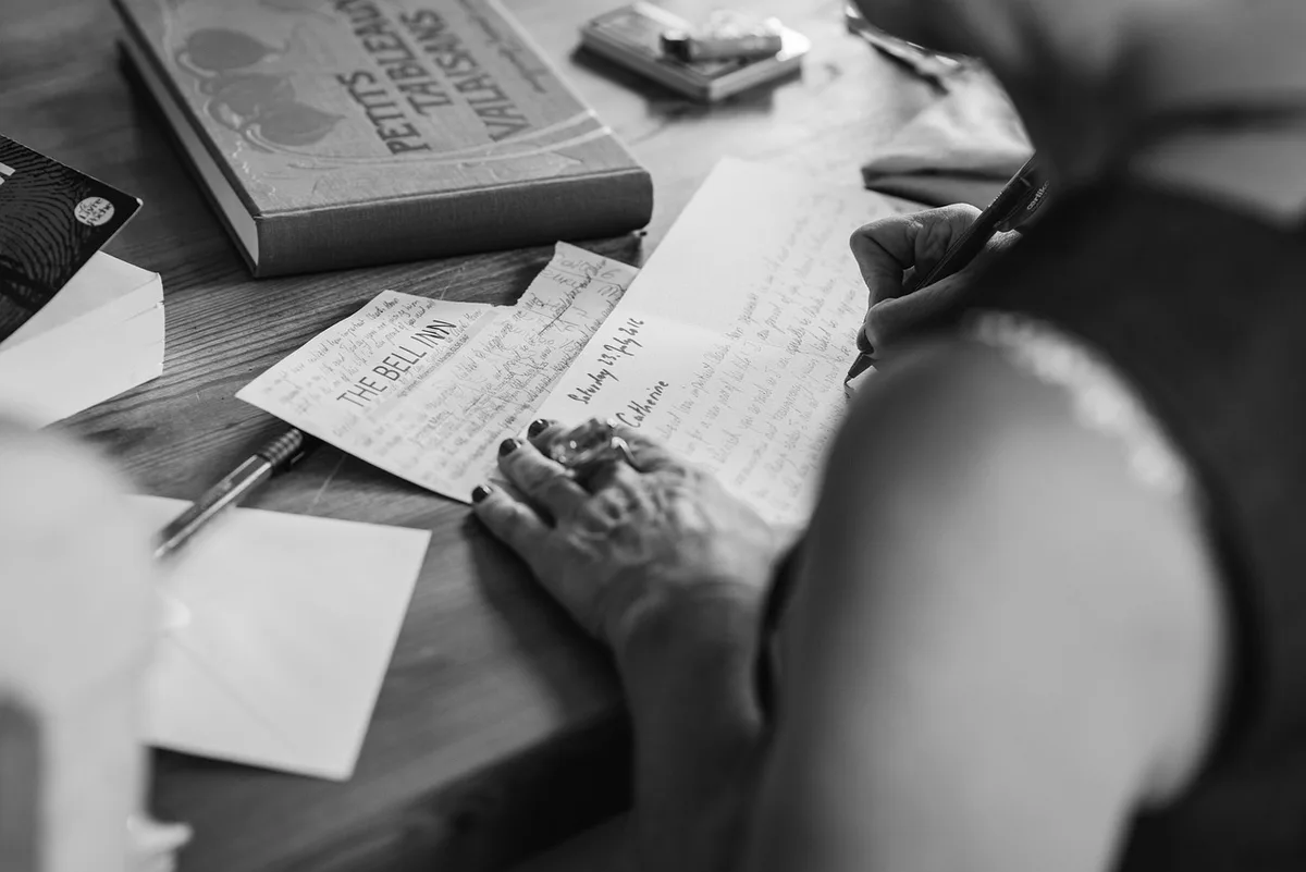 Main écrivant une lettre de réclamation près d'une photocopie de contrat