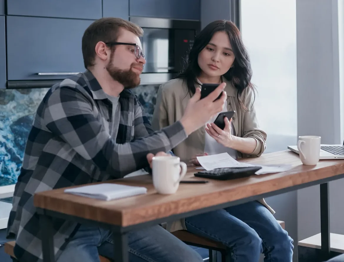 Avis d'échéance et calculatrice posés sur une table de cuisine en pleine journée